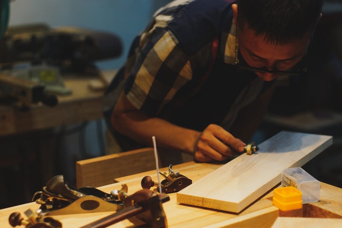 A maker leaning over the workbench in warm evening light.