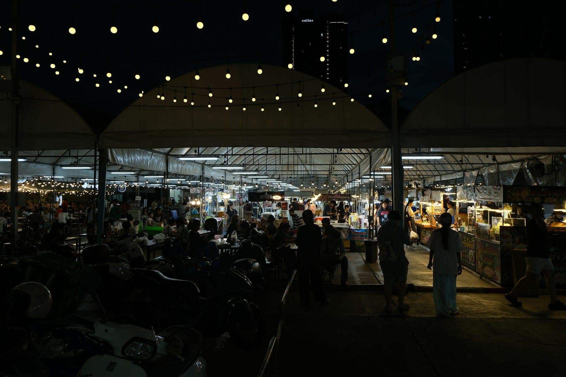 A night market glowing under strings of festoon lights.