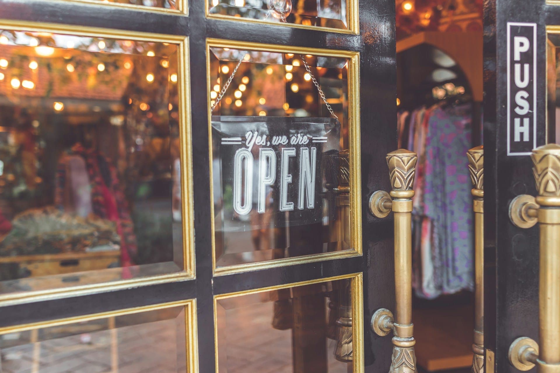 An open sign hanging on the glass door of a small shop.